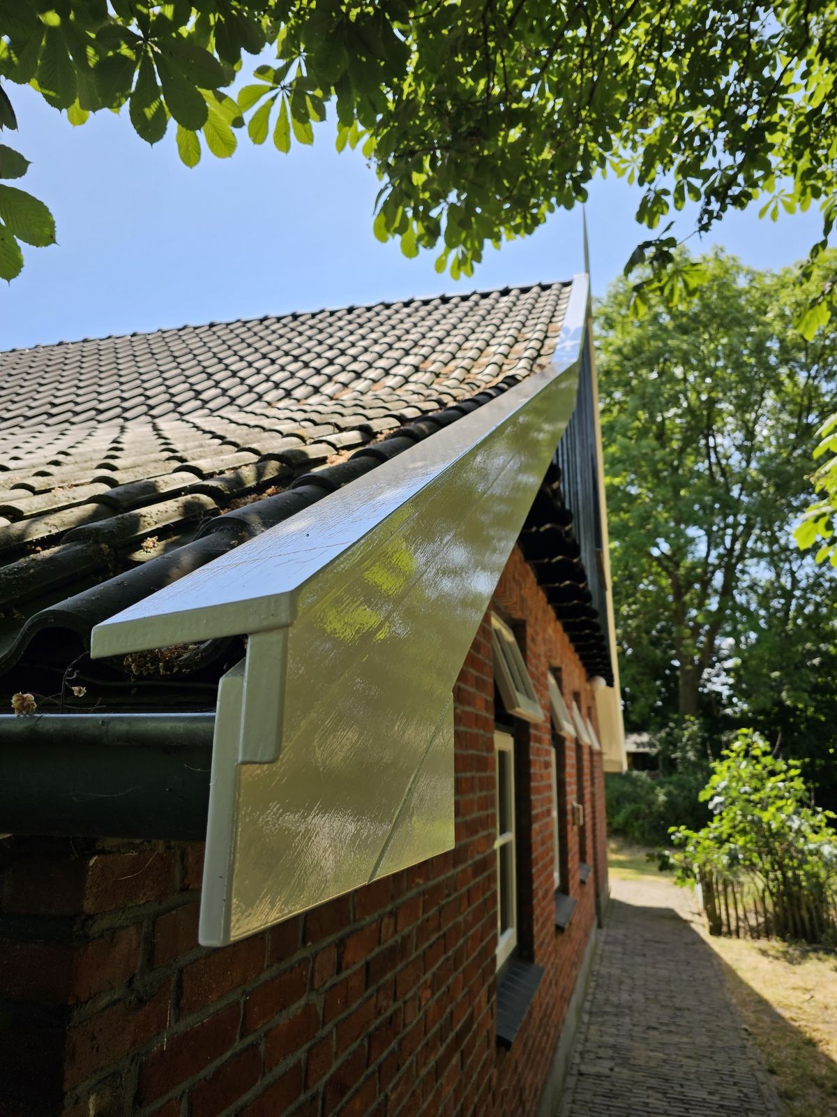 Close-up van een pas geschilderd wit boeiboord onder oude dakpannen