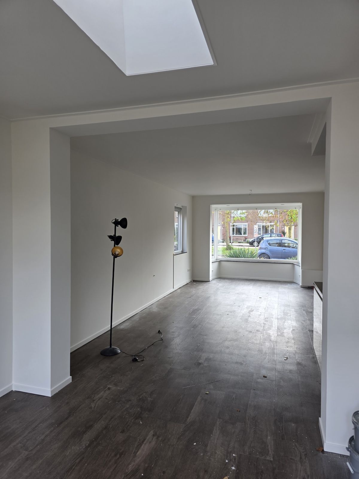 Lange kamer met pas geschilderde witte wanden, plafond en daklicht
