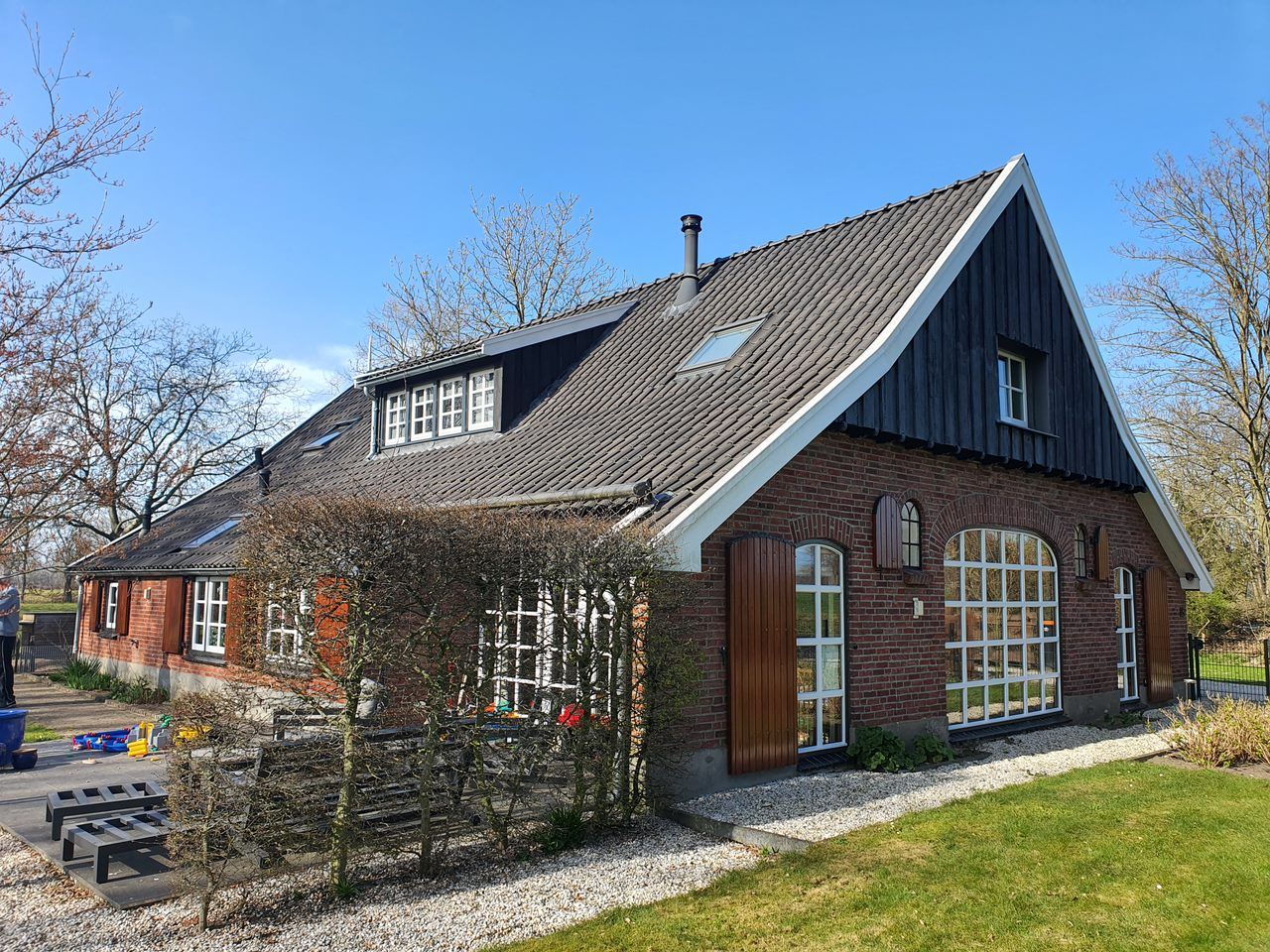 Bakstenen boerderij met een zwart geschilderde houten gevel en witte ramen