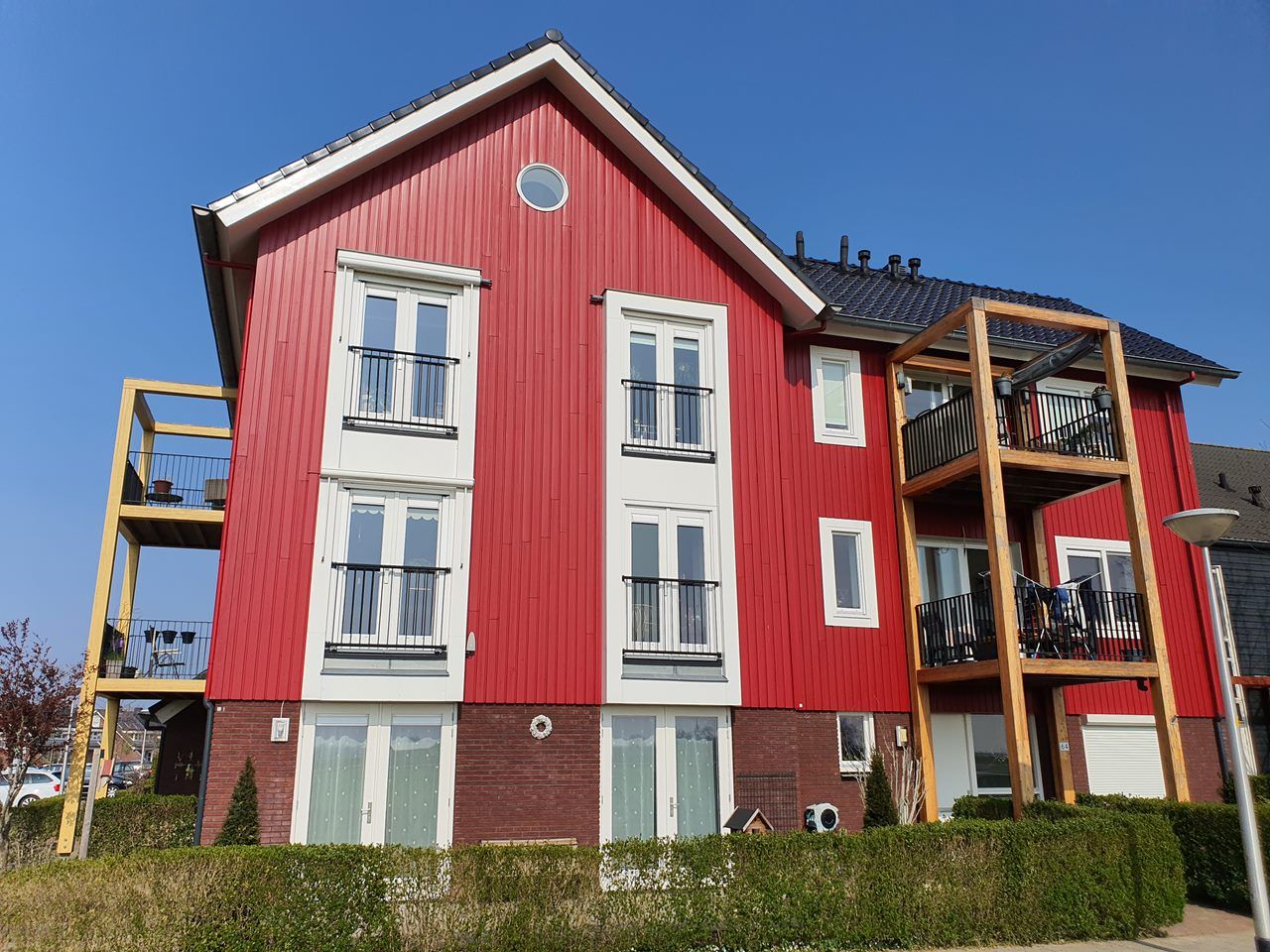 Appartementengebouw met rode houten gevelbekleding en witte kozijnen