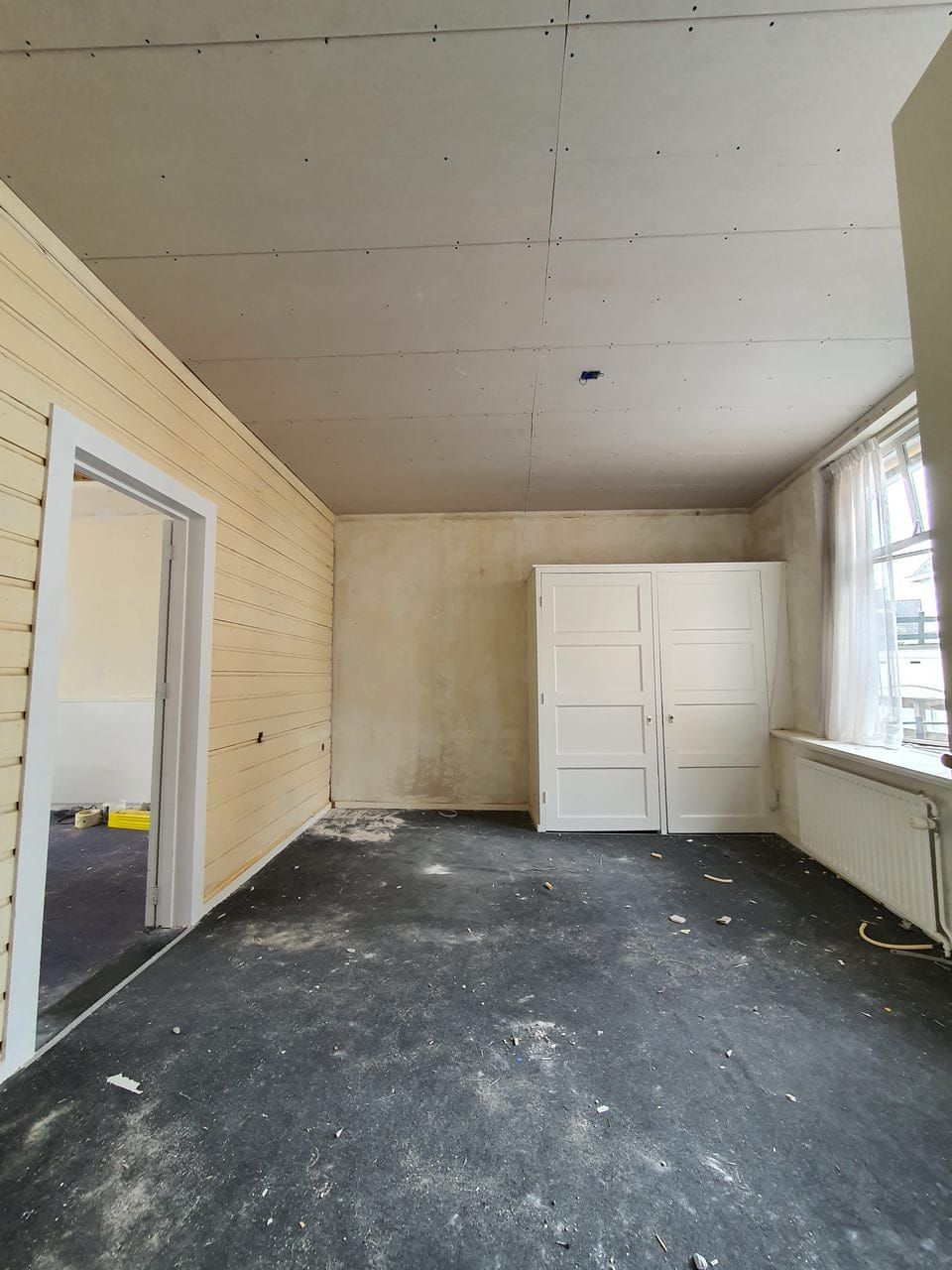 Kamer in de voorbereiding, wanden kaal en de vloer afgedekt