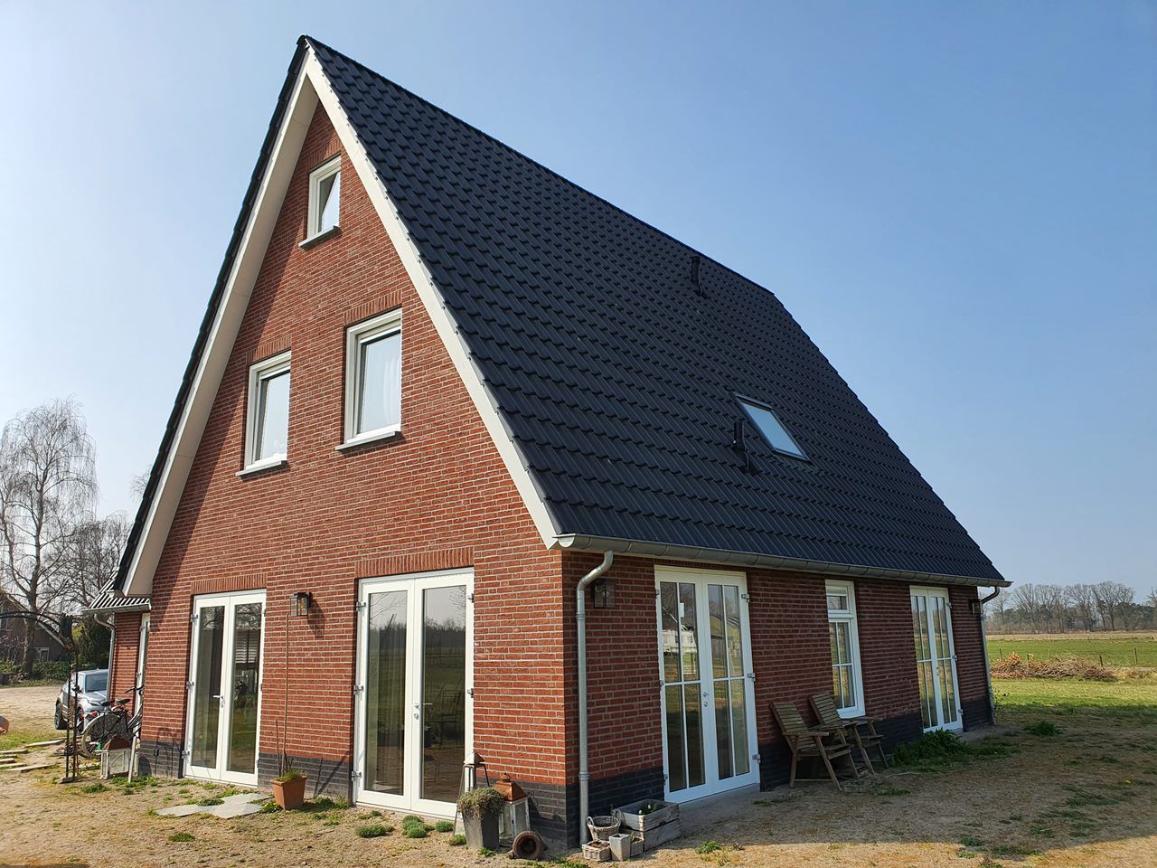 Bakstenen woning met zwart pannendak en witte kozijnen